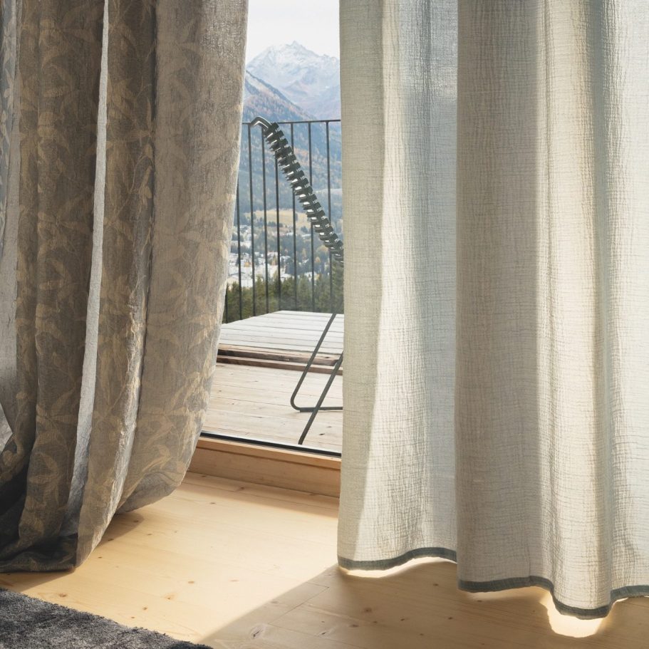 Gardinengestaltung für lichtdurchflutete Räume Transparente Gardine mit floralem Muster vor einem Fenster mit Bergpanorama