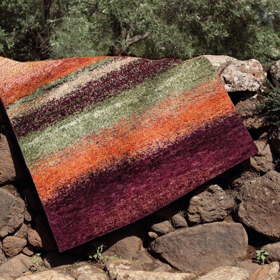 Exklusiver Teppich aus Naturmaterialien Handgefertigter Teppich mit grün-orange-burgunderfarbenem Streifenmuster auf Naturstein