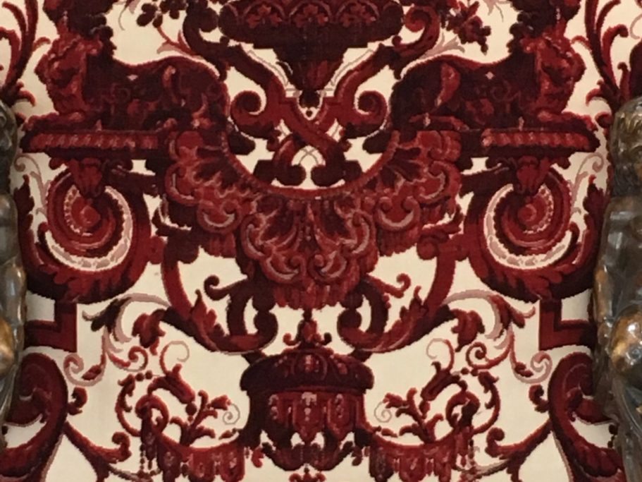 Bezugsstoff-Detail einer venezianischen Manufaktur Detailaufnahme des roten Damastbezugs mit symmetrischem Kronen- und Rankenornament
